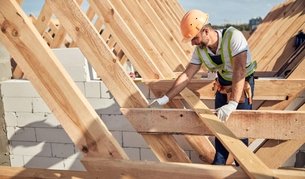 Professional builder in protective equipment building a roof