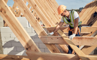 Professional builder in protective equipment building a roof