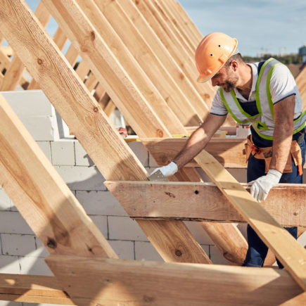 Professional builder in protective equipment building a roof