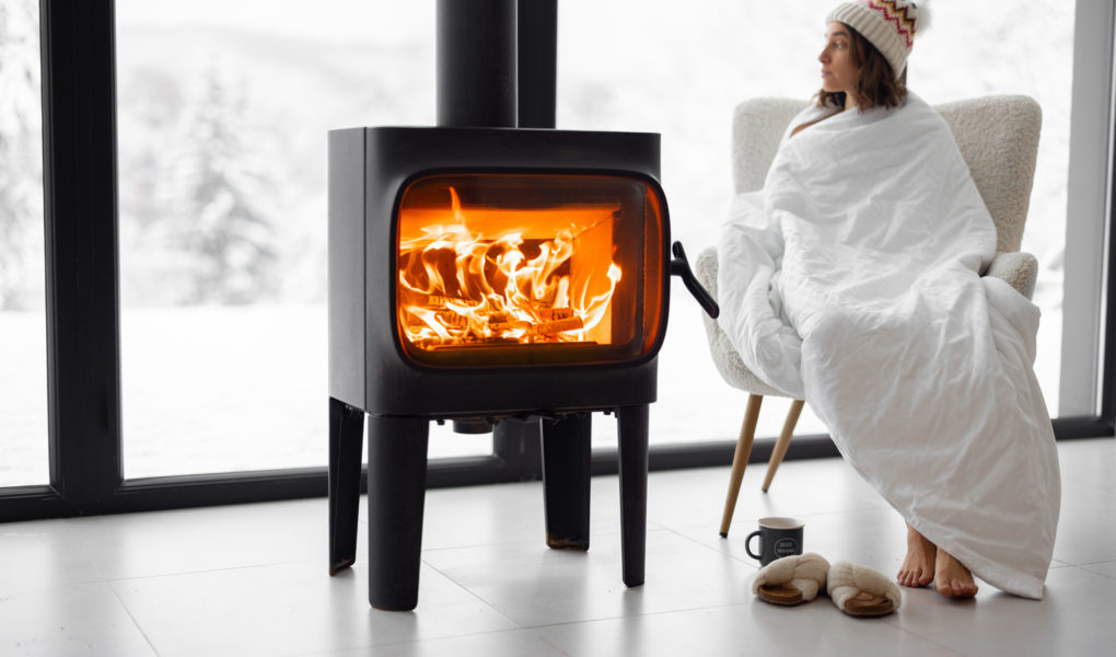 Woman at home with burning fireplace during wintertime on nature