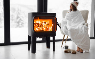 Woman at home with burning fireplace during wintertime on nature
