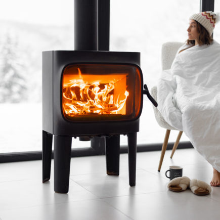 Woman at home with burning fireplace during wintertime on nature