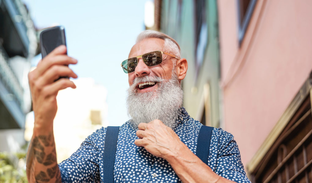 Bearded senior using mobile phone outdoor