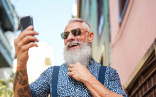 Bearded senior using mobile phone outdoor