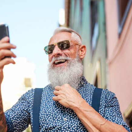 Bearded senior using mobile phone outdoor