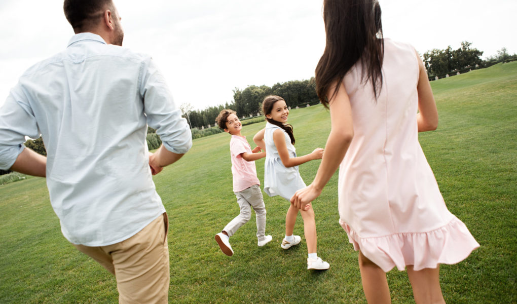 Spending time with kids. Back view of young active family playing together while spending free time