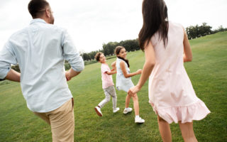 Spending time with kids. Back view of young active family playing together while spending free time