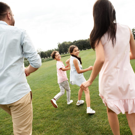 Spending time with kids. Back view of young active family playing together while spending free time