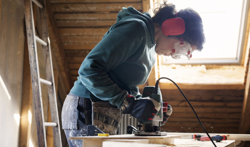 Woman using power tool while renovating old attic