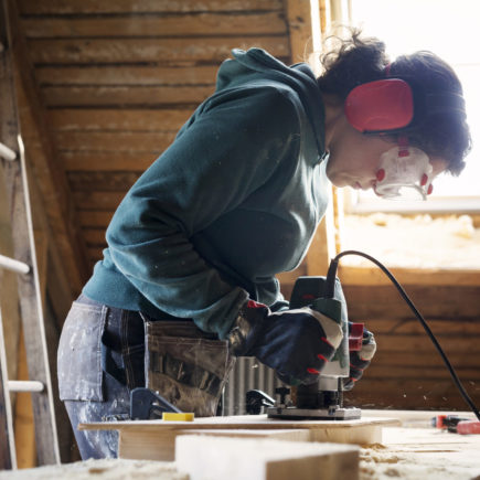 Woman using power tool while renovating old attic